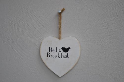 a white heart hanging on a wall with the words bed and breakfast at Fabrikantenvilla in Erkrath