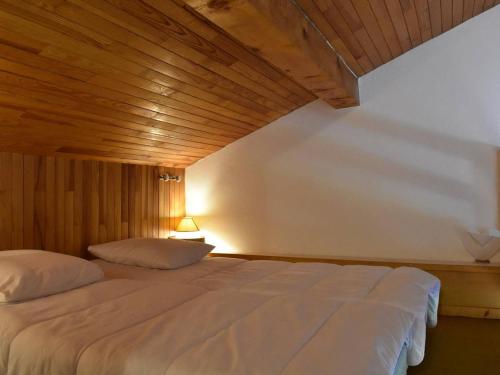 una camera da letto con un grande letto bianco e un soffitto in legno di Chalet à Méribel: 5 pièces, 8-10 pers, proche remontées, pistes et commerces, parking inclus - FR-1-180-188 a Méribel