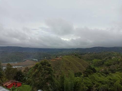 a green hill with a house on top of it at Linda casa con espectacular vista embalse y piedra in Guatapé