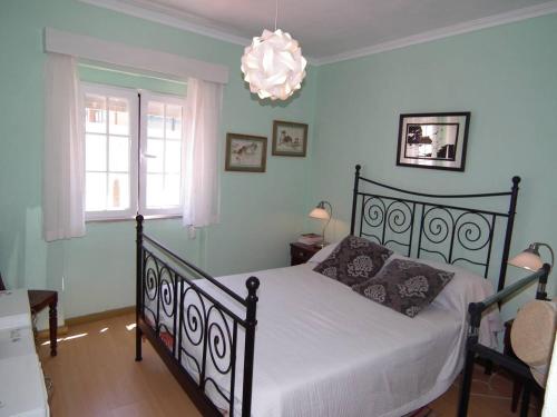 1 dormitorio con cama y lámpara de araña en West Terrace House - Ocean View, en Lourinhã