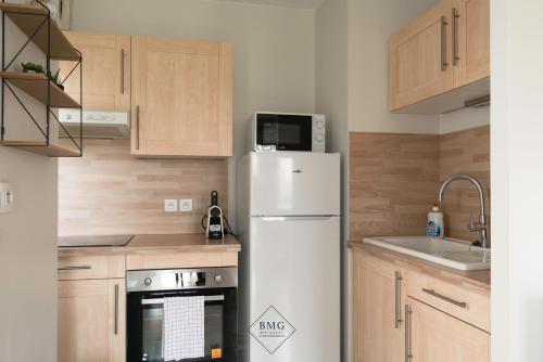 - un réfrigérateur blanc dans une cuisine avec des placards en bois dans l'établissement Prague II Disneyland Bmyguest, à Montévrain