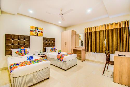 a hotel room with two beds and a desk at Fabhotel Pearl City - Nr Jubilee Enclave, Hitech City in Hyderabad