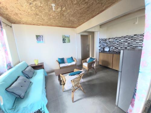 a living room with a blue couch and a kitchen at La Casa Emy in Saint-Leu