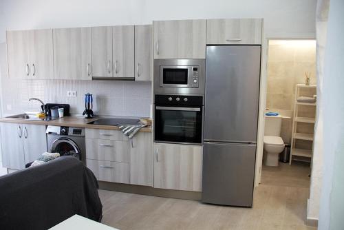 una cocina con nevera de acero inoxidable y armarios en Apartamentos MENBAU, en Gáldar