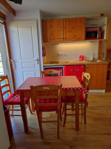a kitchen with a table and chairs and a red kitchen at Les Arolles E23, classé 3 étoiles à Chamrousse 1700 in Chamrousse
