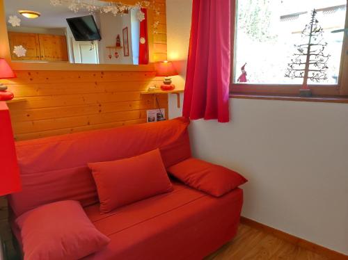 a red couch in a living room with a window at Les Arolles E23, classé 3 étoiles à Chamrousse 1700 in Chamrousse