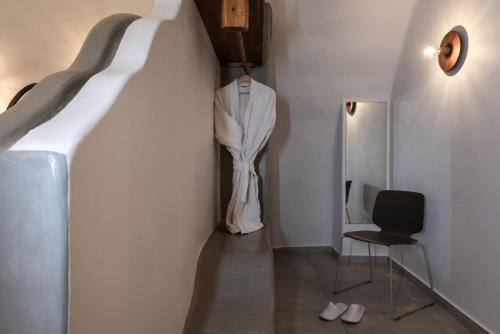 a hallway with a dress hanging on a wall and a chair at Kasimatis by La Perla - Adults Only in Imerovigli