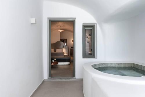 a white bathroom with a tub in a room at Kasimatis by La Perla - Adults Only in Imerovigli