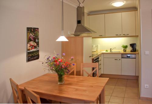une cuisine avec une table en bois et un vase de fleurs. dans l'établissement Residenz Ostseestrand, à Kühlungsborn