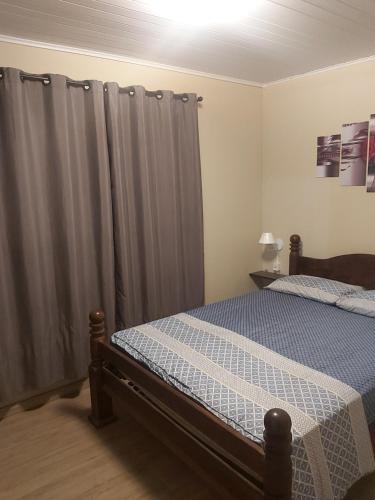 a bedroom with a bed and a gray curtain at Casa de Temporada Gramado in Gramado