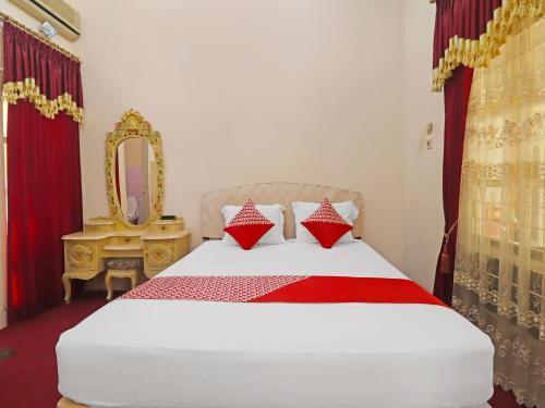 ein Schlafzimmer mit einem Bett mit einem Spiegel und einem Bett mit einem sidx sidx sidx in der Unterkunft OYO 2899 Ardilia Bandara Syariah in Jambi