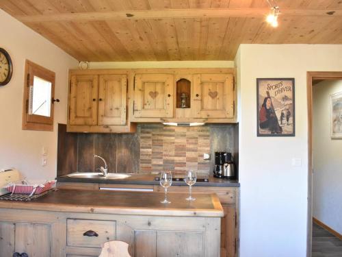 - une cuisine avec des placards en bois et 2 verres à vin dans l'établissement Appartement 3 pièces proche pistes avec balcon et ski-room - FR-1-180-153, à Méribel