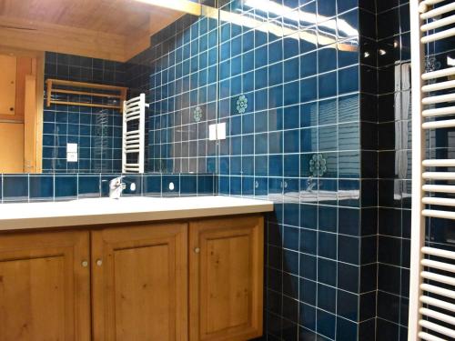 La salle de bains est pourvue de carrelage bleu, d'un lavabo et d'un miroir. dans l'établissement Studio Montagne 6 Pers, Méribel Centre, Proche Commerces et Pistes - FR-1-180-118, à Méribel