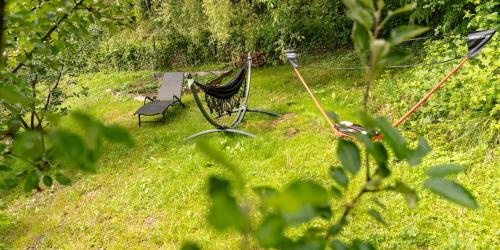 a hammock in the middle of a field of grass at STRÓŻÓWKA SKI&SPA Domek nad rzeką z ogrodem i jacuzzi,narty. in Stróża