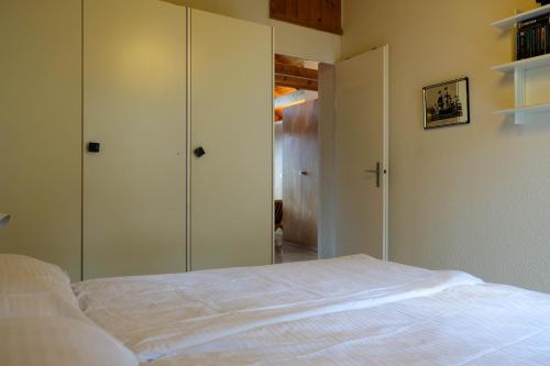 a bedroom with a white bed and glass closets at Seewohnung 1 in Spiez