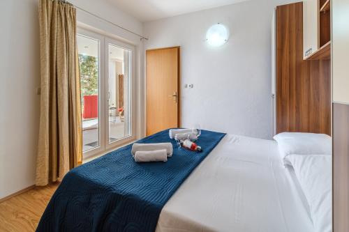 a bedroom with a large white bed with two stuffed animals on it at Rooms Plaža Divuje in Murvica