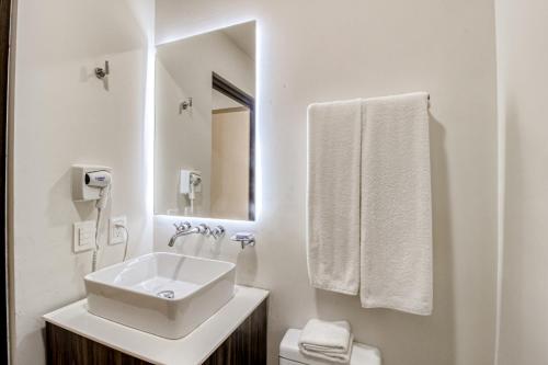 La salle de bains blanche est pourvue d'un lavabo et d'un miroir. dans l'établissement Moonlight 002 at Aldea Zama, à Tulum