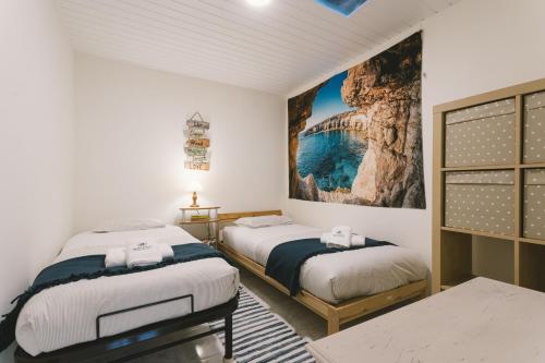 ein Schlafzimmer mit zwei Betten und einem Gemälde an der Wand in der Unterkunft Best Houses 71 - Casa das Ondas in Peniche
