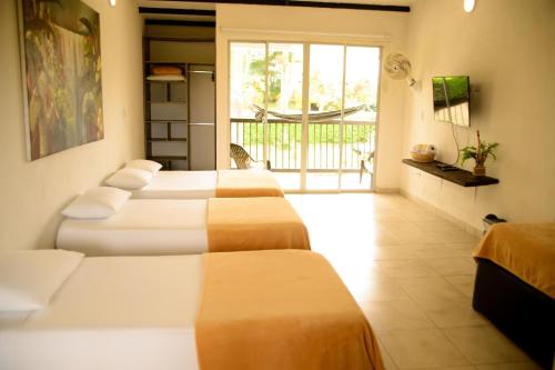 a row of beds in a room with a balcony at Finca Hotel Loma Verde in Quimbaya