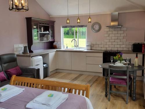 a kitchen and living room with a table and chairs at The Snuggery Broadclyst in Exeter