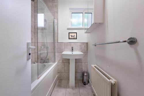 y baño blanco con lavabo y ducha. en Stay in Islington in style 3BDR apt Nr Upper St en Londres