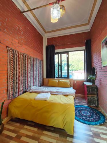 a bedroom with a yellow bed in a brick wall at Du Gia View Homestay in Làng Cac
