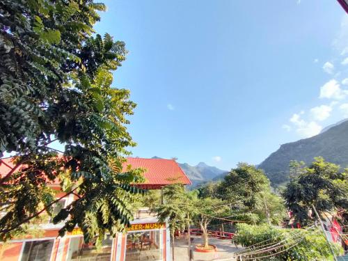 a building with a red roof with mountains in the background at Du Gia View Homestay in Làng Cac