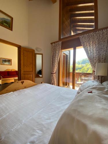 a bedroom with a large white bed with a large window at Apparthotel Mountain River Resort in Val dʼIlliez
