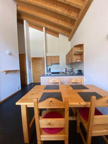 uma cozinha com uma mesa de madeira e cadeiras em Apparthotel Mountain River Resort em Val dʼIlliez