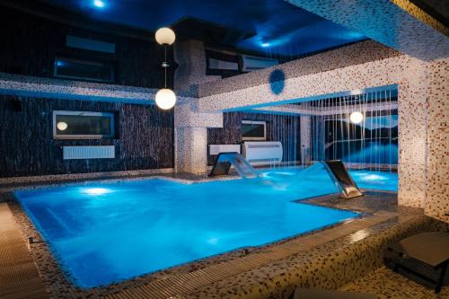Marmaros Apart-Hotel & Spa في بوكوفِل: مسبح كبير في غرفة الفندق مع إضاءة زرقاء