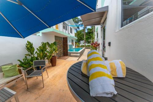 a patio with a table and a blue umbrella at Casa Verde Hotel - Steps to the Beach, Pool, Restaurant & Bar in Rincon