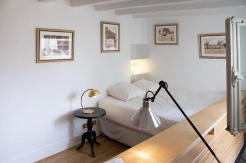 een slaapkamer met een bed en een tafel met een lamp bij Haut MaraisJolie duplex 33m2… in Parijs