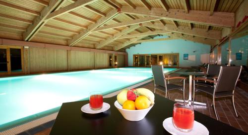 a pool with a table with a bowl of fruit and drinks at Palace Hotel Wellness & Beauty in Bormio