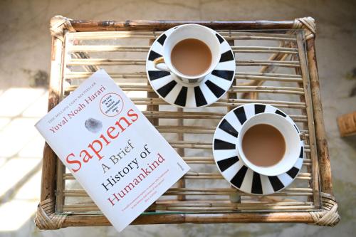 Una bandeja con dos tazas de café y un libro. en Nahorjan Tea Homestay, en Bokākhāt