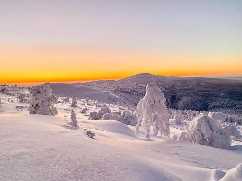 a snow covered mountain with a sunset in the background at Arctic Lodges Lapland Ski In Family Studio, Wi-Fi, National Park - Lapland Villas in Pyhätunturi