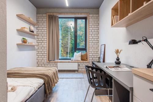 a room with a bed and a desk and a window at SHED Vilnius Coliving in Vilnius