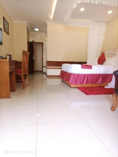 a bedroom with a bed and a desk and a table at Meru Slopes Hotel in Meru