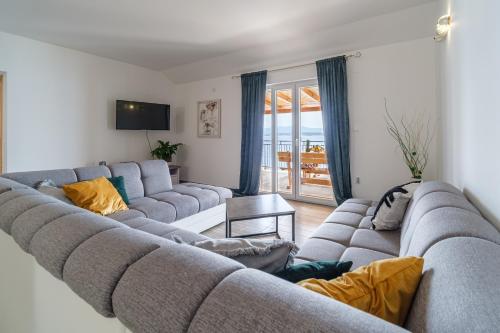 a living room with a large couch and a television at Rooms Plaža Divuje in Murvica