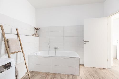 een witte badkamer met een bad en een ladder bij JAMA - Stilvoll&Modern, Zentral, Uni, Freies Parken, Große Gruppen, WLAN in Erlangen