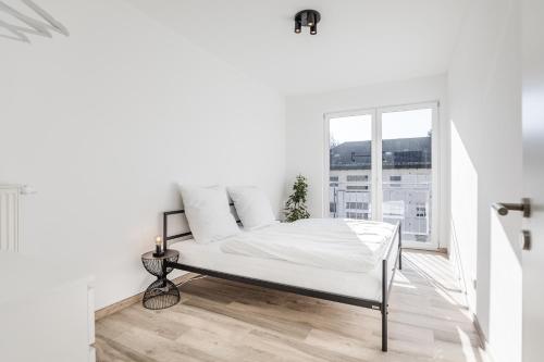 Bett in einem weißen Zimmer mit Fenster in der Unterkunft JAMA - Stilvoll&Modern, Zentral, Uni, Freies Parken, Große Gruppen, WLAN in Erlangen