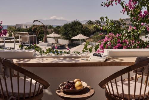 a table with a bowl of fruit on a table with chairs at Dionysos Seaside Resort Ios in Mylopotas