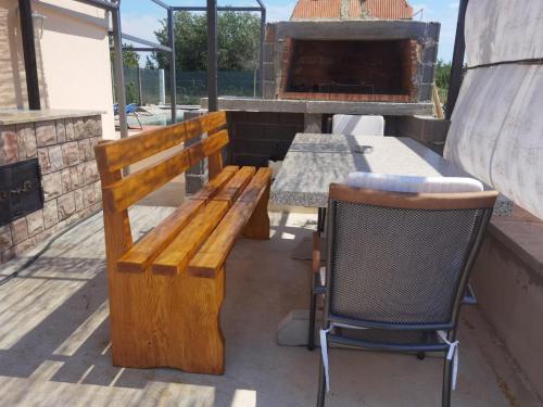 a wooden bench sitting next to a table and a pizza oven at Villa Bali - Aladinici in Stolac