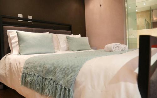 Una gran cama blanca con un animal de peluche. en The Franklin Luxury Apartments en Johannesburgo
