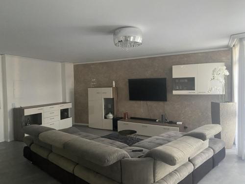 uma sala de estar com um sofá grande e uma televisão em Luxus 2 Zimmer Ferienwohnung em Lauchheim