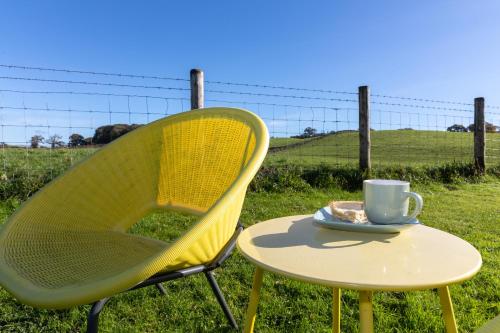 a yellow chair and a table with a cup of coffee at The Orchards in Kendal