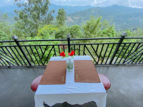 a table with a vase with red flowers on it at Berghaus Bungalow in Ella