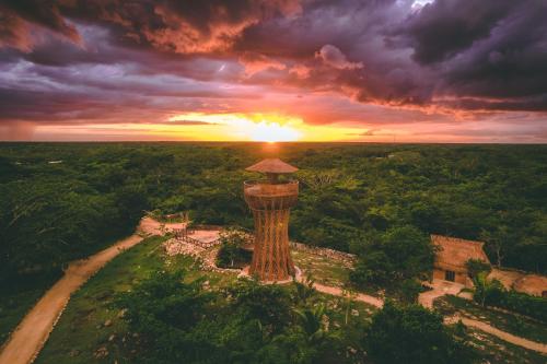 an aerial view of a tower with the sunset in the background at Destino Mío Mayan Jungle Retreat in Tekit