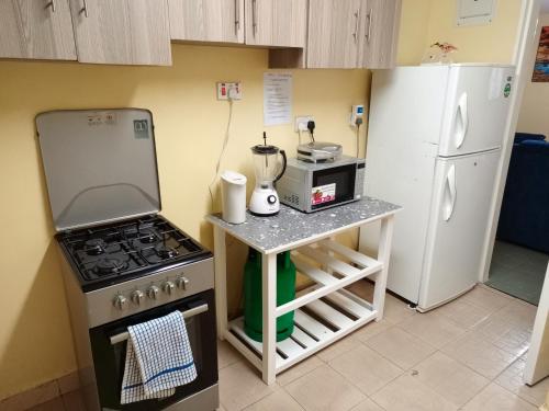 una pequeña cocina con fogones y nevera. en GCurtway Homes Nyayo 3 bedroom, en Nairobi