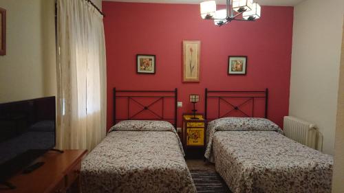 two beds in a room with red walls at Posada La Reja in Malpica