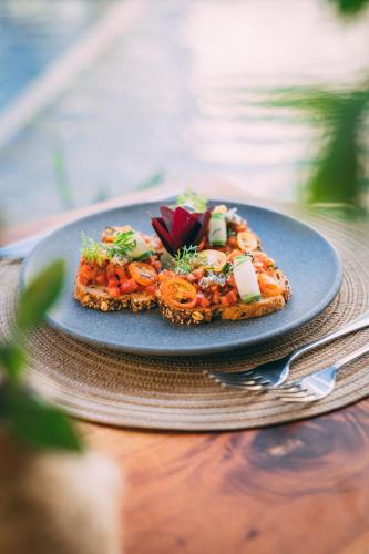 a slice of pizza on a blue plate on a table at Destino Mío Mayan Jungle Retreat in Tekit